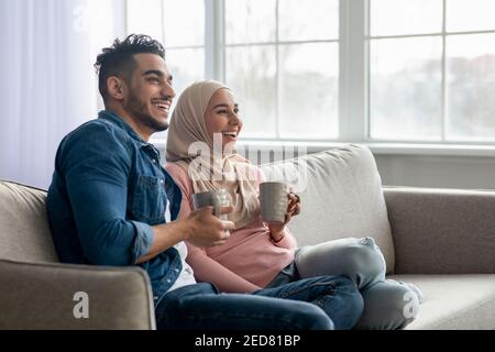 Beautiful muslim couple drinking tea, looking at copy space Stock Photo