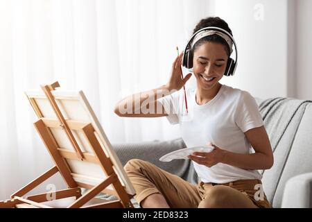 Happy woman listening to music and enjoying drawing Stock Photo
