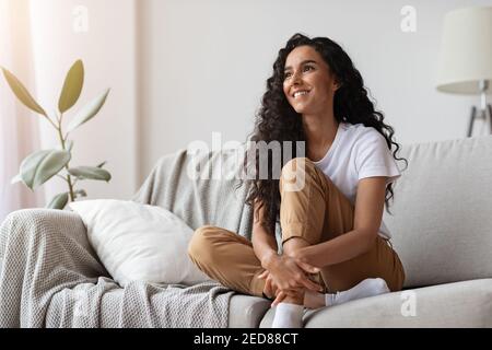 Joyful young lady sitting on couch at home Stock Photo