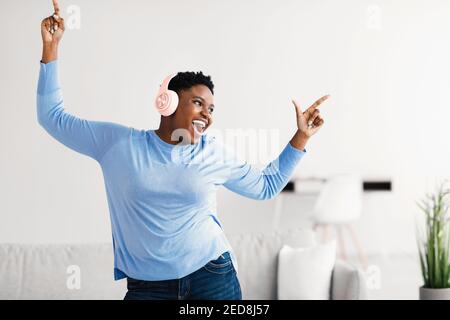 Black lady listening to music in headphones and dancing Stock Photo