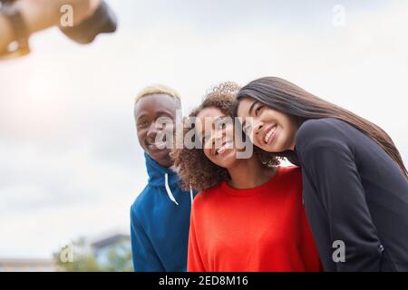 Multi ethnic friends outdoor on photo shooting looking at camera. Diverse group people Afro american asian spending time together Multiracial male female student meeting outdoors for photo Stock Photo
