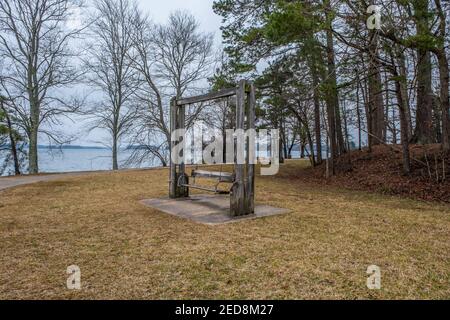 Along the trail at the lake are a couple of swinging bench seats and other benches alongside the lake at Lake Lanier in Georgia Stock Photo