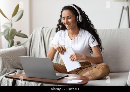 Cheerful lady attending online course, using laptop and wireless headset Stock Photo