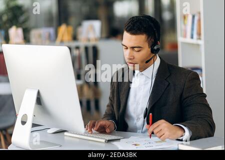 Focused hispanic successful businessman or business mentor looks at the financial graph during online business conference with business partners Stock Photo