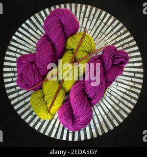 Fuchsia  and chartreuse yarn with knitting needles crossed on black and white table Stock Photo