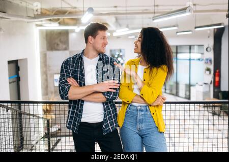 Smiling business partners or university friends. Young adult multiracial employees or students discussing project or exam, smiling. Caucasian man and african american woman work or study together Stock Photo