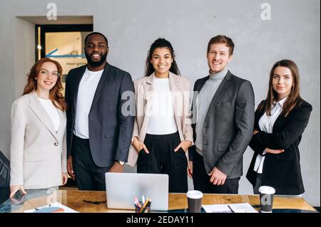 Portrait of successful multiracial business team standing in modern office. Group of business people work together, smiling. Confident male and female employees look at the camera, teamwork concept Stock Photo