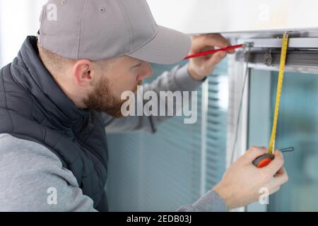 young man installing window shades at home Stock Photo