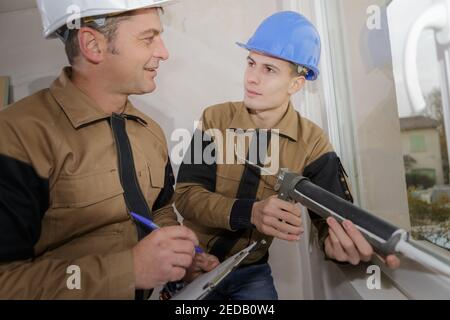 technician and apprentice using a silicon gun Stock Photo