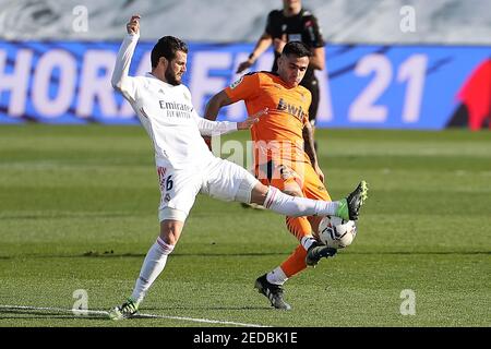 Madrid, Spain. 14th Feb, 2021. Real Madrid's Nacho (L) vies with Valencia's Maxi Gomez during a Spanish football league match between Real Madrid and Valencia CF in Madrid, Spain, on Feb. 14, 2021. Credit: Edward F. Peters/Xinhua/Alamy Live News Stock Photo