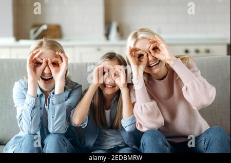 Funny photo of grandmother daughter and granddaughter. Cheerful caucasian grandmother daughter and granddaughter are having fun at home, indulge, and enjoy joint leisure Stock Photo