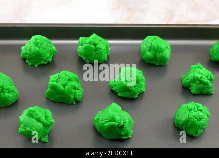 Balls of raw green Saint Patrick's Day cookie batter placed on nonstick baking sheet Stock Photo