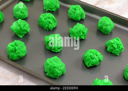 Balls of raw green Saint Patrick's Day cookie batter placed on nonstick baking sheet Stock Photo