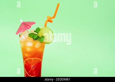 Colorful alcoholic cocktail drink in the glass decorated with sliced lime, mint and umbrella Stock Photo