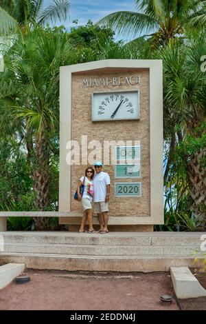 Tourist couple pose in front of Miami Beach sign on South Beach updated to 2020. Stock Photo