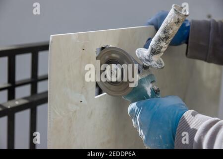 Finishing works cutting ceramic tiles a square hole in the tile with an angle grinder Stock Photo