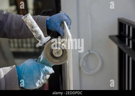 Man cutting square hole for electrical outlet in the tile shape using angle grinder power tools Stock Photo