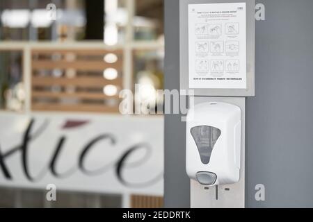 Hand sanitizer machine in public place near the wall at the entrance to shopping center. Automatic dispenser with alcohol gel sanitizer Stock Photo