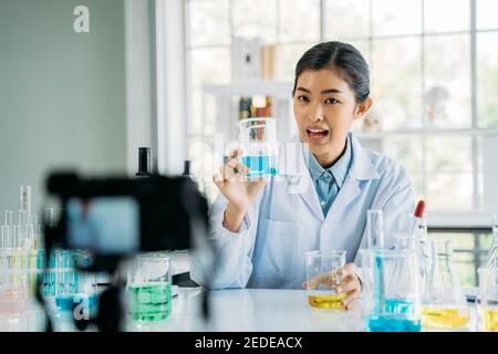 Portrait of young female doctor wearing lab coat recording online video class and vlog on medical research and science experiments in laboratory Stock Photo