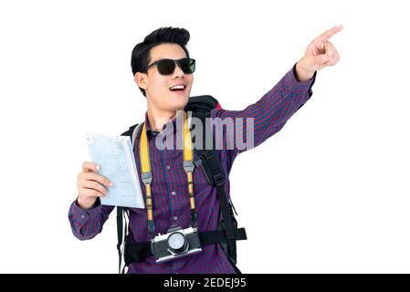 Portrait of amazed young tourist Asian man with sunglasses pointing and using map while carrying a backpack in studio white background Stock Photo