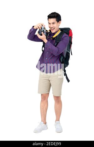 Isolated Portrait of happy young attractive asian tourist man in casual attire carrying a backpack taking a photo with his camera