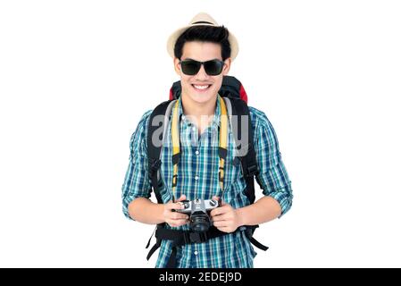 Portrait of smiling young handsome Asian tourist man carrying backpack and holding camera isolated on white background studio shot Stock Photo