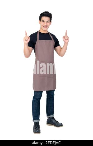 Isolated portrait of a young attractive male asian barista in brown apron smiling and  pointing hand upward Stock Photo