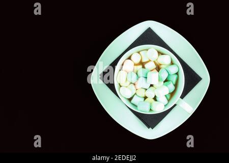 Black coffee and marshmallows in a white cup. Copy space for text. Coffee and marshmallows on black isolated background Stock Photo