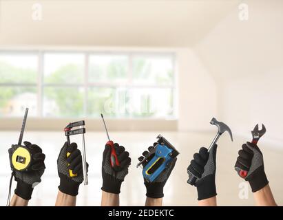 Many hands with different construction tools indoors Stock Photo
