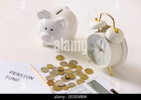 Piggy bank with coins, alarm clock and calculator on white background. Concept of pension Stock Photo