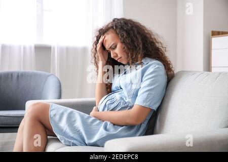 Stressed pregnant African-American woman at home Stock Photo