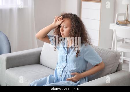 Stressed pregnant African-American woman at home Stock Photo