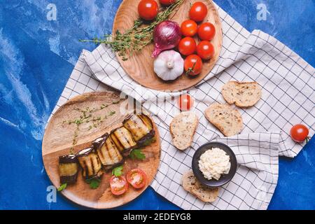 Plates with tasty grilled eggplant and vegetables on color background Stock Photo