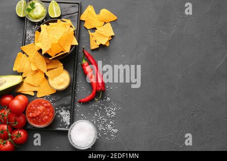 Tasty nachos and sauces on dark background Stock Photo