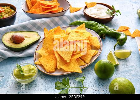 Plates with tasty nachos and sauces on color background Stock Photo