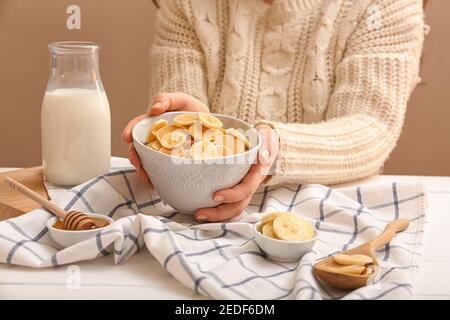 Woman holding bowl of tasty pancakes with banana on color background Stock Photo