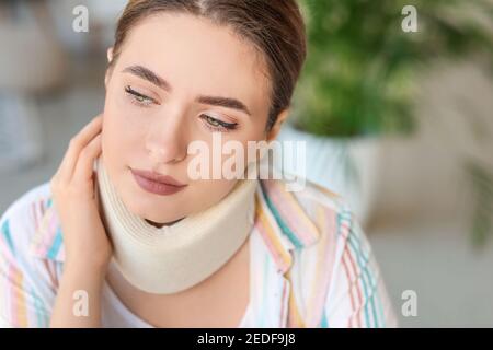 Young woman with cervical collar on neck at home Stock Photo