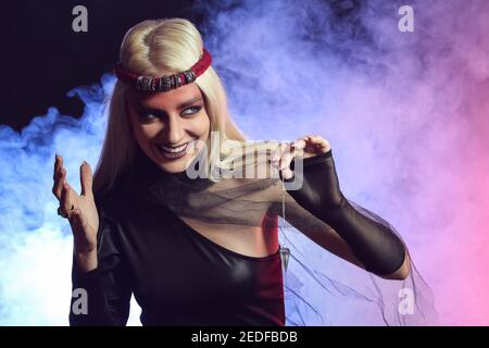 Young witch performing ritual on dark background Stock Photo