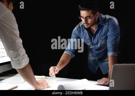 Asian architect team staying late at night in office discussing  project at meeting table Stock Photo