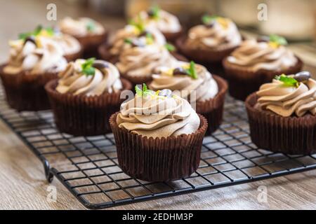Homemade chocolate cupcakes with tiramisu cream, chocolate coffee beans and mint. Selective focus. Stock Photo