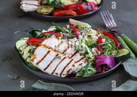 Grilled halloumi cheese with grilled vegetables and green salad, green concrete background. Healthy food concept. Selective focus. Stock Photo