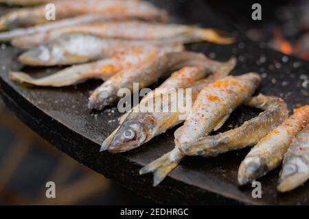 Process of cooking european smelt fish on black brazier at food festival Stock Photo