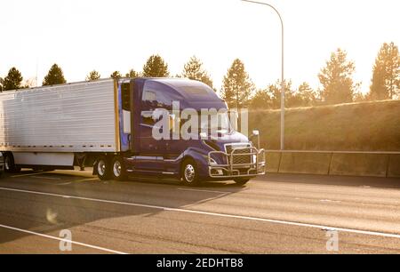 Powerful Big rig industrial classic blue semi truck tractor transporting frozen commercial cargo in refrigerated semi trailer running for delivery on Stock Photo