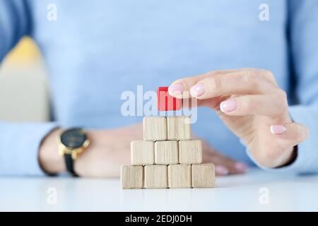 Woman building pyramid from wooden cubes closeup Stock Photo