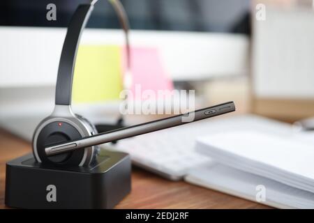 Headphones with microphone standing on wooden table in office closeup Stock Photo