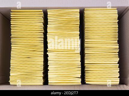 Top view of three stacks of yellow mail envelopes neatly packed in a large shipping box Stock Photo