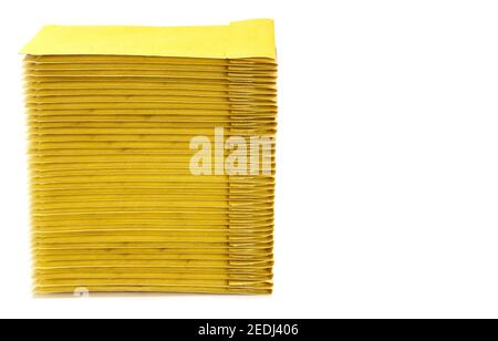 Stack of yellow padded envelopes isolated on white. Side view, copy space. Stock Photo