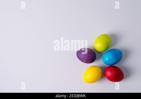 Easter background. Painted chicken eggs in yellow, green, blue, red, purple colors lie on a light background. Step 5 Stock Photo