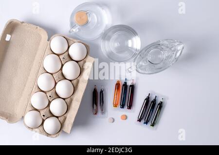 Preparations for Easter, the concept of coloring eggs, materials for coloring lie on a light background - eggs in a box, dyes, utensils with water and Stock Photo