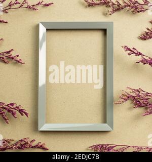 Empty photo frame with pink misty blue dry flowers on brown kraft paper background. top view, copy space Stock Photo